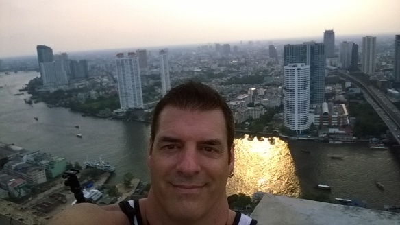 Selfie at the top of the building, with the sunset reflecting on the river below
